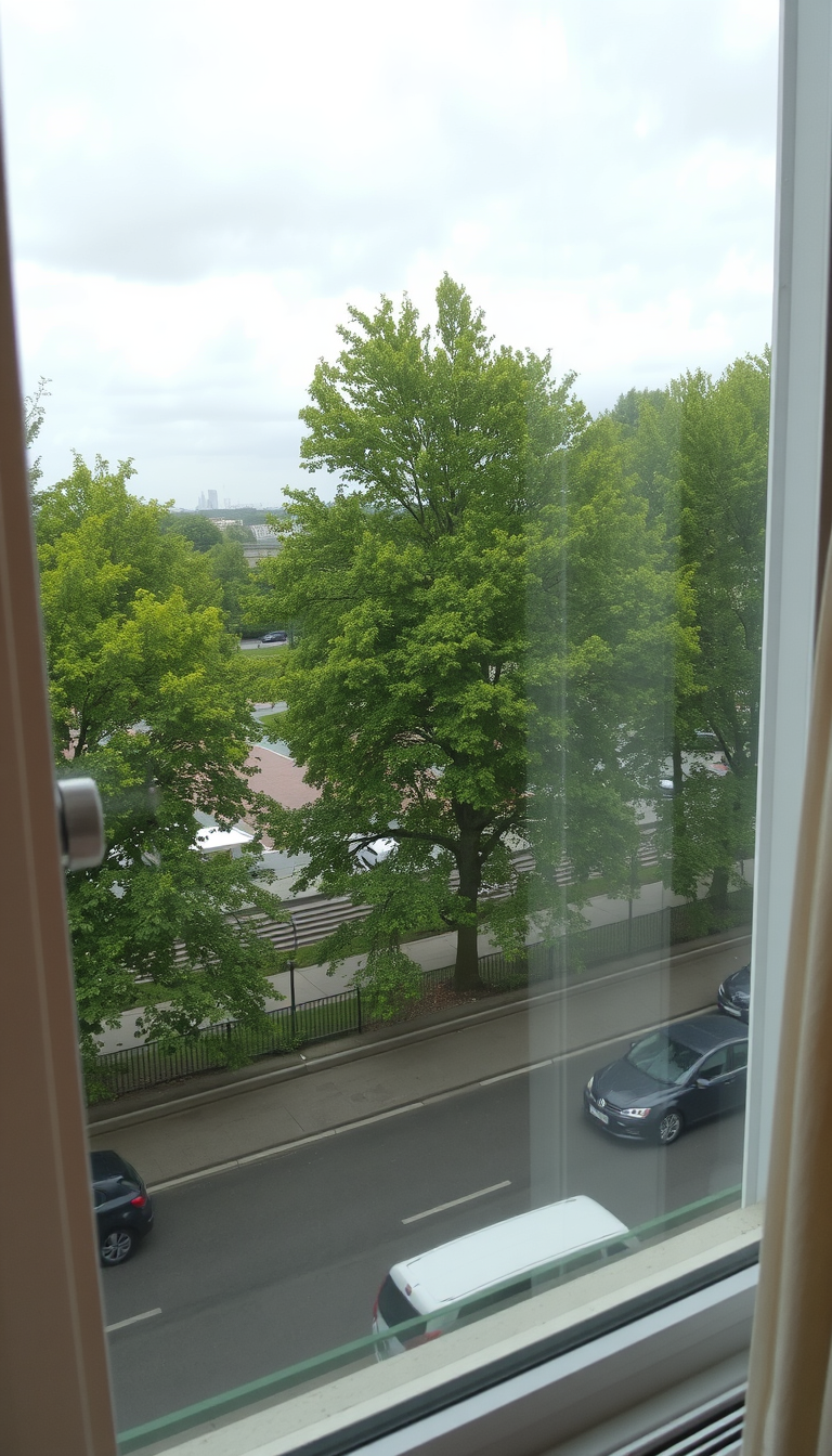 Main art studio: From the apartment window, there is a view of a central square in Warsaw. Outside the window, there are lush green trees and the square is clearly vis